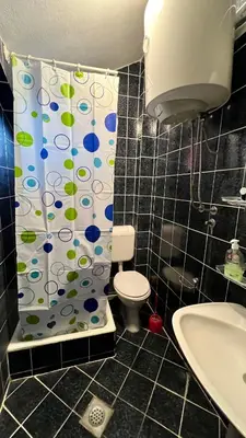 a bathroom with a toilet and a shower curtain at Apartments Holiday in Budva