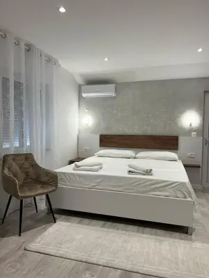a bedroom with a large white bed and a chair at Apartments Hillside in Ulcinj