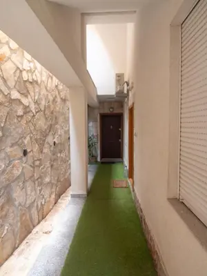 a hallway with green flooring and a stone wall at Mum's Apartment in Petrovac na Moru