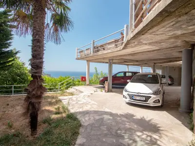a white car parked under a building with a palm tree at Mum's Apartment in Petrovac na Moru