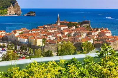a town with red roofs on a hill next to the ocean at Royal Montesun Apartments in Budva