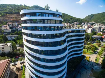 a tall blue and white building with a city at Royal Montesun Apartments in Budva