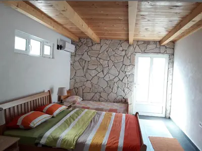 a bedroom with two beds and a stone wall at Pensions Airport in Podgorica
