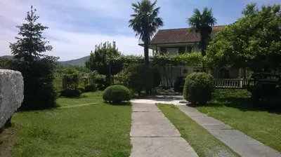 a house with a walkway in front of a yard at Pensions Airport in Podgorica