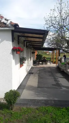 a building with a covered walkway with flowers on it at Pensions Airport in Podgorica
