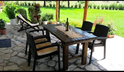 a wooden table with chairs and a bottle of wine at Pensions Airport in Podgorica