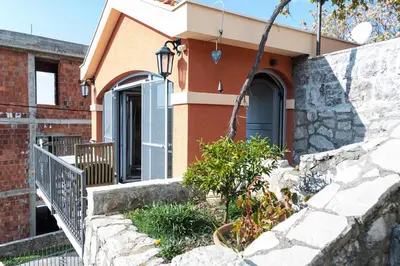 a house with a stone retaining wall and a staircase at Apartmani Kamena Ruža in Budva