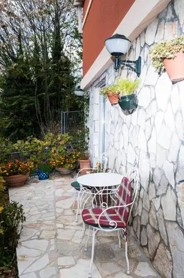 a patio with a table and chairs on a stone wall at Apartmani Kamena Ruža in Budva