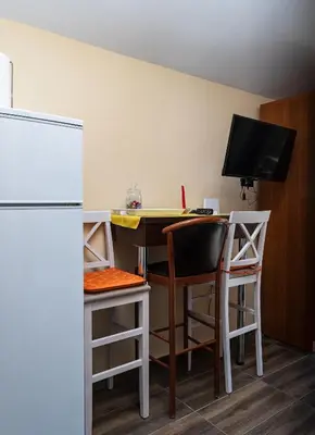 a kitchen with a desk and a refrigerator and a table and chairs at Apartmani Kamena Ruža in Budva