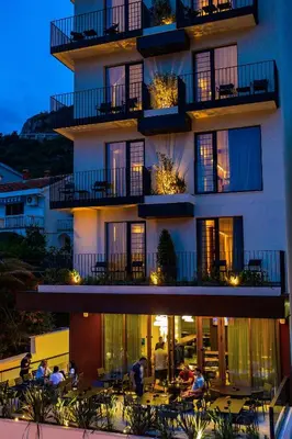 a building with people sitting at tables in front of it at Hotel Kalos in Budva