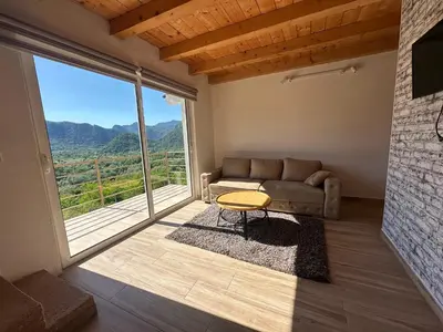 a living room with a couch and a large window at Brioni in Virpazar