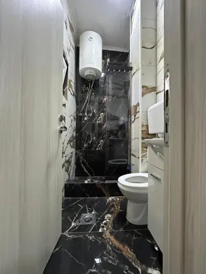 a bathroom with a toilet and a black marble floor at Brioni in Virpazar