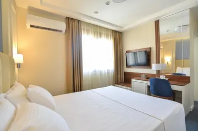 a hotel room with a white bed and a desk at Vistamar Hotel & Apartments in Budva