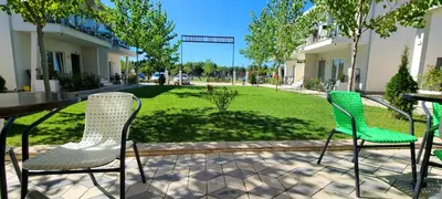 a patio with two chairs and a table and a lawn at Casa Al Mare in Ulcinj