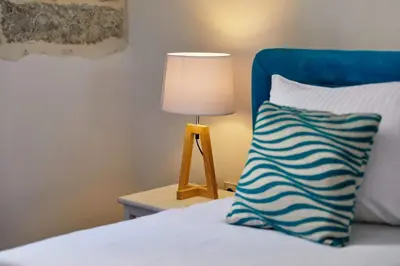 a bed with a blue headboard and a lamp on a table at La Rocca Apartment Old Town Kotor in Kotor