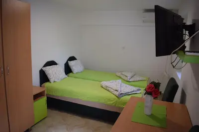 a room with a green bed with a tv and a table at OLD TOWN STUDIOS in Budva