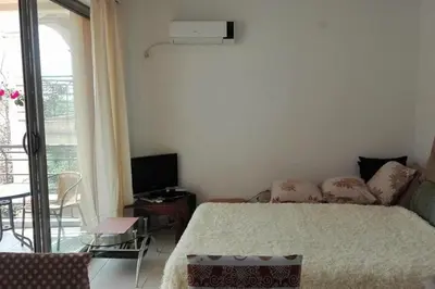 a bedroom with a bed and a tv and a balcony at Bečići Sunset Apartments in Becici