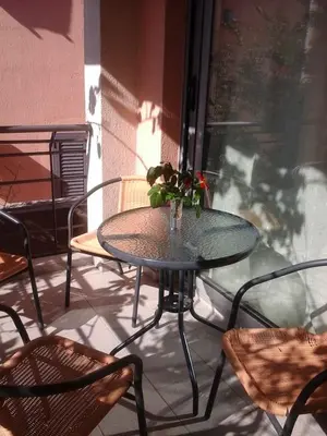 a glass table with a vase of flowers on a patio at Bečići Sunset Apartments in Becici
