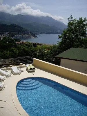 a swimming pool with chairs and a view of a lake at Bečići Sunset Apartments in Becici
