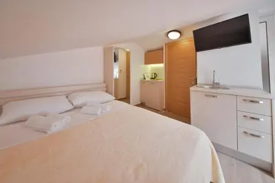 a bedroom with a white bed and a flat screen tv at Apartmani Ljubo Rafailovic 2 in Rafailovici