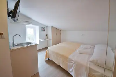 a white bedroom with a bed and a sink at Apartmani Ljubo Rafailovic 2 in Rafailovici