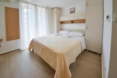 a bedroom with a large bed with white sheets at Apartmani Ljubo Rafailovic 2 in Rafailovici