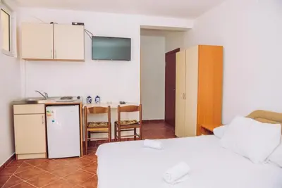 a room with a bed and a kitchen with a refrigerator at Apartmani Lasta in Dobra Voda