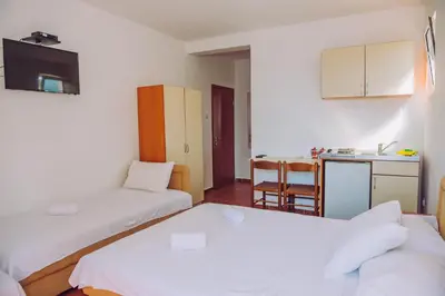 a small room with two beds and a kitchen at Apartmani Lasta in Dobra Voda