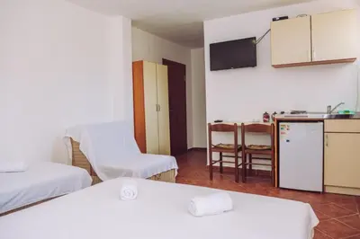 a room with two beds and a kitchen with a refrigerator at Apartmani Lasta in Dobra Voda