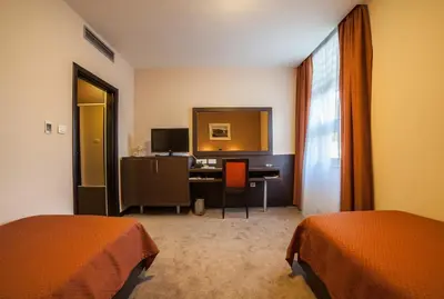 a room with two beds and a desk with a mirror at Hotel Terminus in Podgorica