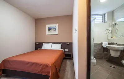 a bedroom with a bed and a bathroom with a sink at Hotel Terminus in Podgorica