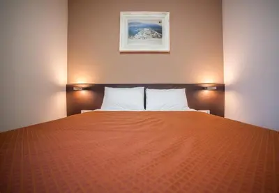 a bedroom with a bed with an orange blanket at Hotel Terminus in Podgorica