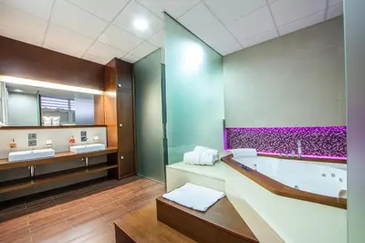 a bathroom with a tub and two sinks and a mirror at Hotel Terminus in Podgorica