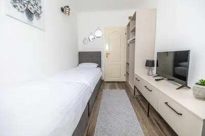 a white bedroom with a bed and a tv at Apartments Irena in Becici