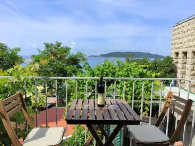 a wooden table with a bottle of wine on a balcony at Fisherman House Apartments in Rafailovici