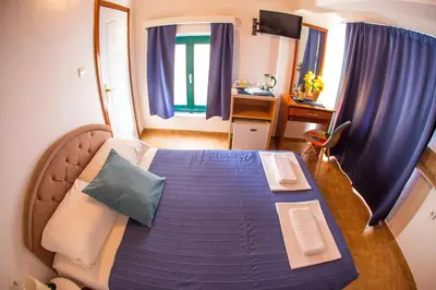 a bedroom with a bed with blue sheets and blue curtains at Fisherman House Apartments in Rafailovici