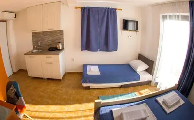a small room with a bed and a kitchen at Fisherman House Apartments in Rafailovici