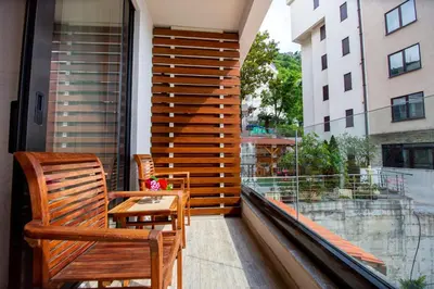 a balcony with two chairs and a table and a window at Fisherman House Apartments in Rafailovici