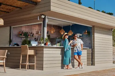 a man and a woman standing in front of a bar at ĀNANTI Resort, Residences & Beach Club - The Leading Hotels of the World in Sveti Stefan