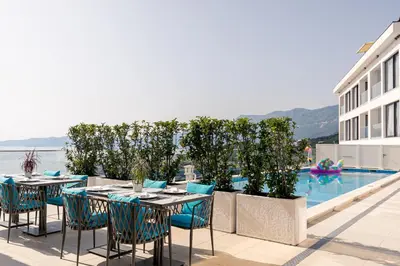 a patio with tables and chairs next to a swimming pool at ĀNANTI Resort, Residences & Beach Club - The Leading Hotels of the World in Sveti Stefan