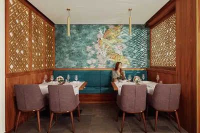 a woman sitting at a table in a restaurant at ĀNANTI Resort, Residences & Beach Club - The Leading Hotels of the World in Sveti Stefan