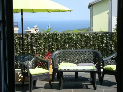 three chairs and a table and an umbrella on a patio at Apartments Mila Krimovica in Krimovice