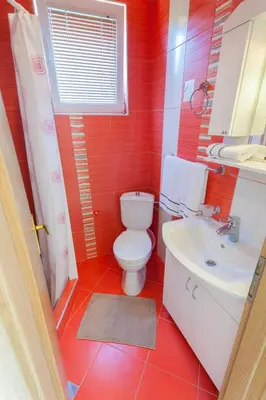 a red bathroom with a toilet and a sink at Apartments Mila Krimovica in Krimovice