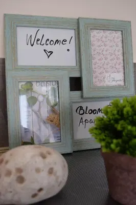 a table with framed pictures and a plant and a plant at Apartman Bloom in Bar