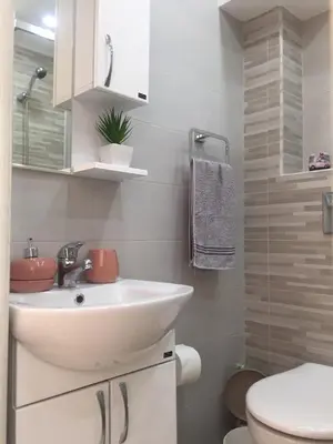 a white bathroom with a sink and a toilet at Apartman Bloom in Bar