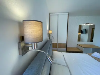a hotel room with a bed and a lamp on the wall at Guest house Villa Slavica in Sveti Stefan