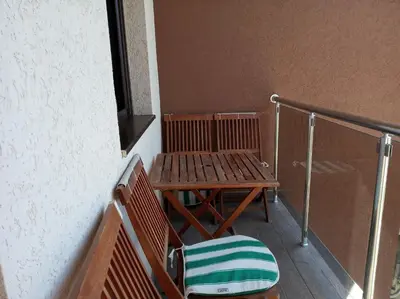 a wooden bench and a chair on a balcony at Faith Apartman in Budva