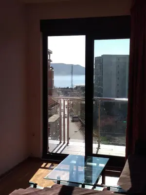 a room with a glass table in front of a large window at Faith Apartman in Budva