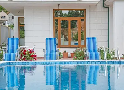 a swimming pool with blue columns in front of a house at Villa Ramonte in Cetinje