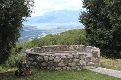 a stone fountain on top of a hill with a mountain at Forest Apartments in Kotor